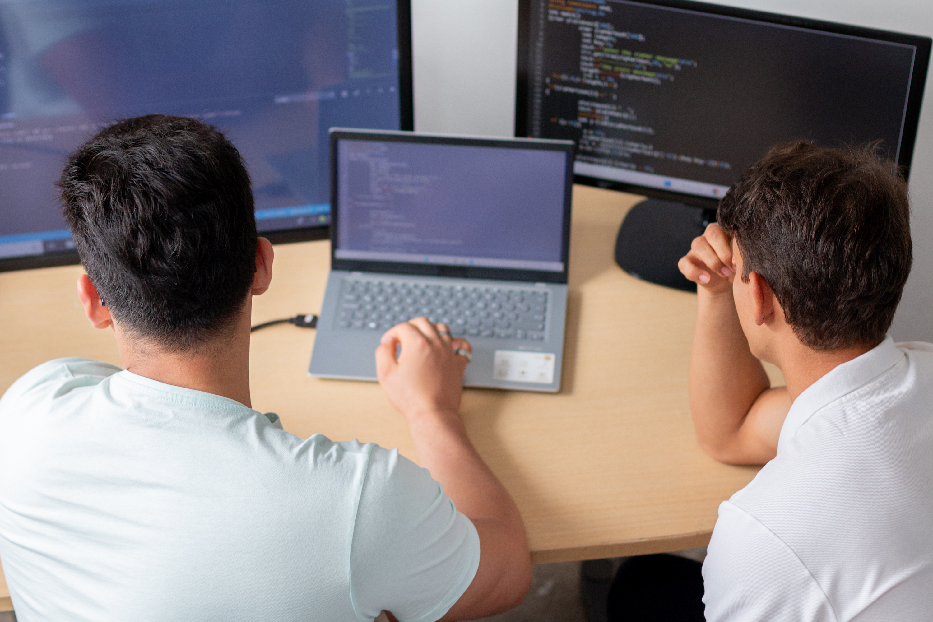 two men in office cooperating writing code